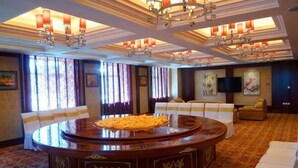 A spacious room with a round table, comfortable seating, and a television. - Mohe International Conference Center (Mohe)
