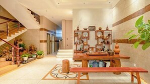 A spacious lobby with a wooden bench, a staircase, and a wall decorated with various items. - Qujing 1 +1 Express Hotel (Qujing)