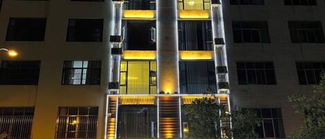 Un edificio de varios pisos con señalización iluminada y ventanas.