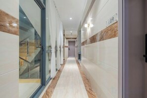 A hotel corridor with a glass door entrance, a staircase, and a marble-tiled floor. - Qujing 1 +1 Express Hotel (Qujing)