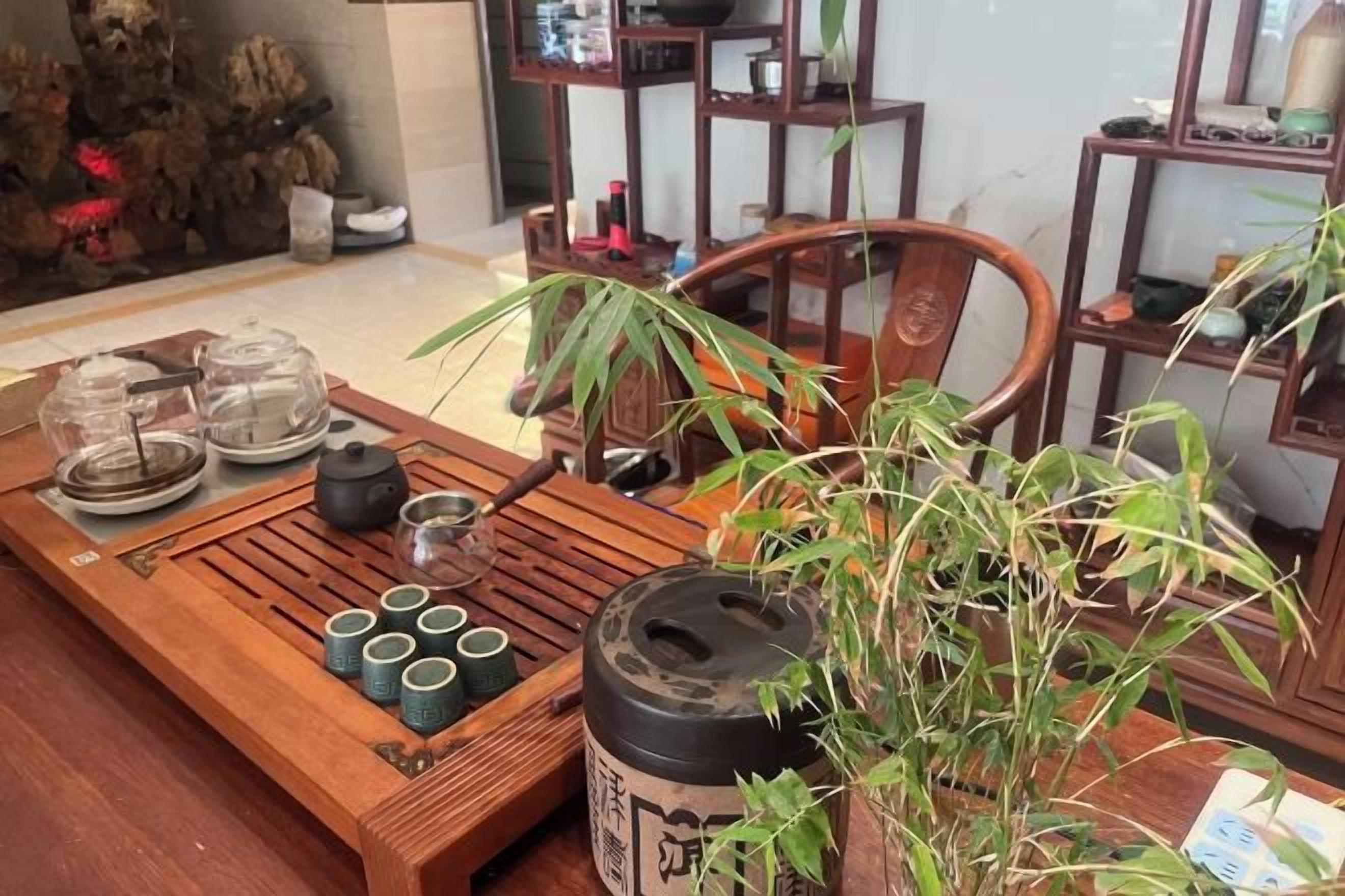 Une table en bois avec une théière, des tasses et une plante.