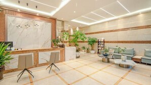 A modern lobby with a reception desk, seating area, and potted plants. - Qujing 1 +1 Express Hotel (Qujing)