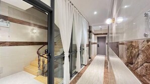A modern hotel hallway with a glass door, white curtains, a marble floor, and a staircase with wooden steps. - Qujing 1 +1 Express Hotel (Qujing)