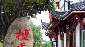Ein traditionelles Gebäude mit einem Ziegeldach und einem Stein mit roten Schriftzeichen.