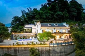 A multi-story house with a swimming pool, surrounded by lush greenery and a steep hillside. - Jiuhua Mountain Tanxiangge Homestay (Roushen Hall) (Qingyang)