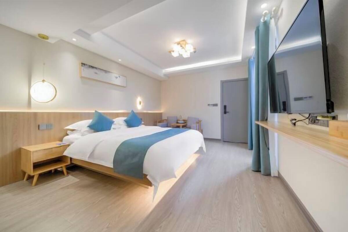 A modern hotel room with a bed, bedside table, and a TV.