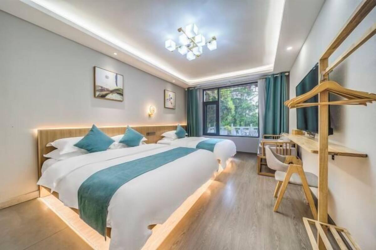 A modern hotel room with a large bed, bedside tables, a desk, and a view of the outdoors.