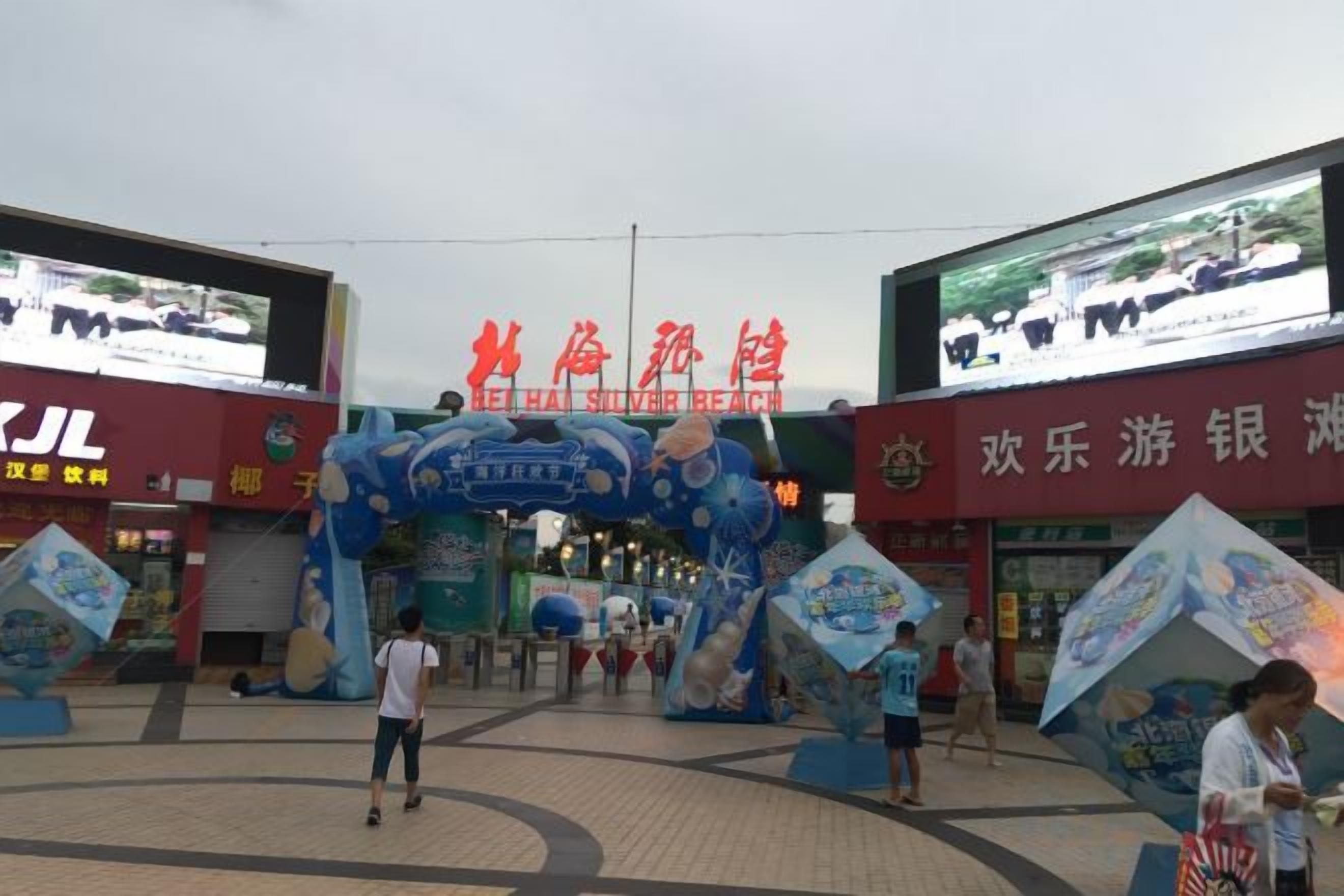 A commercial area with a large archway entrance, signage for a silver beach, and various shops.