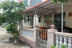 A residential building with a covered porch, a gated entrance, and a small garden area. - Yintan Home Apartment (Beihai)