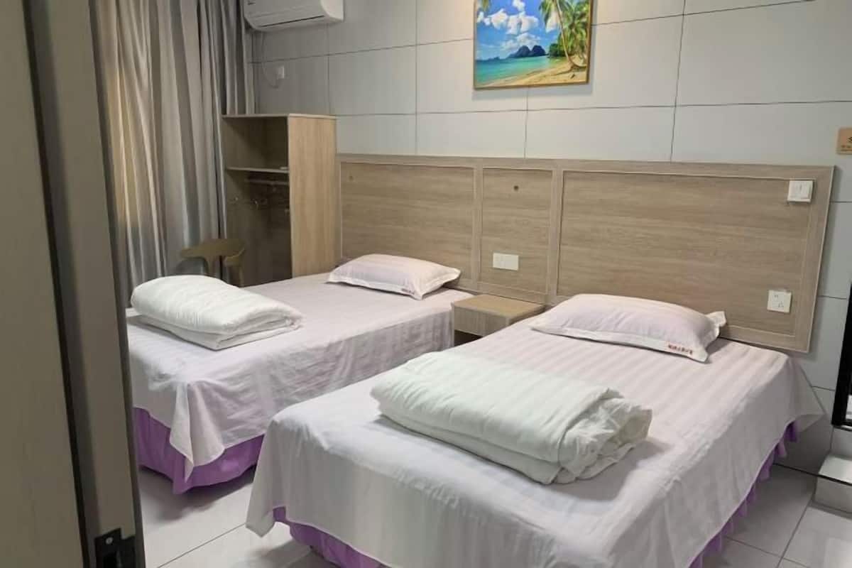 Quarto de hotel com duas camas, um guarda-roupa e um quadro na parede.