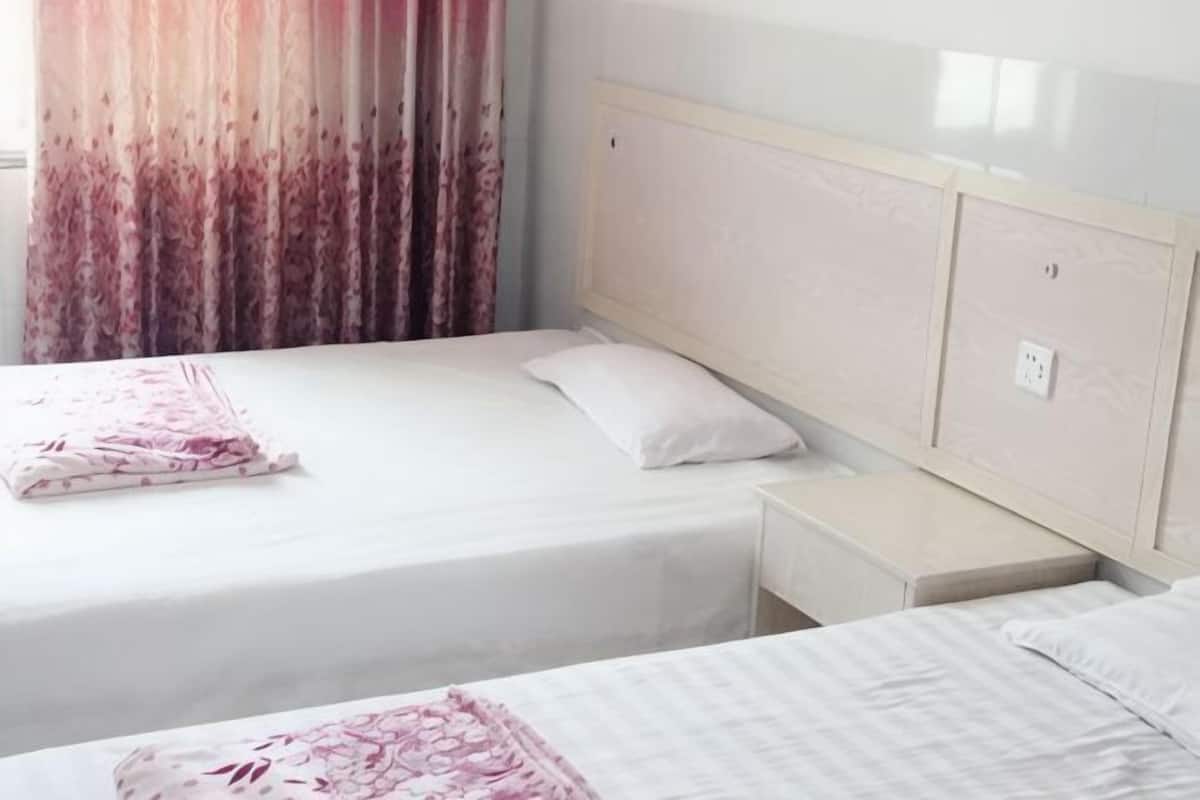 Quarto de hotel com duas camas, uma mesa de cabeceira e painel de cabeceira.