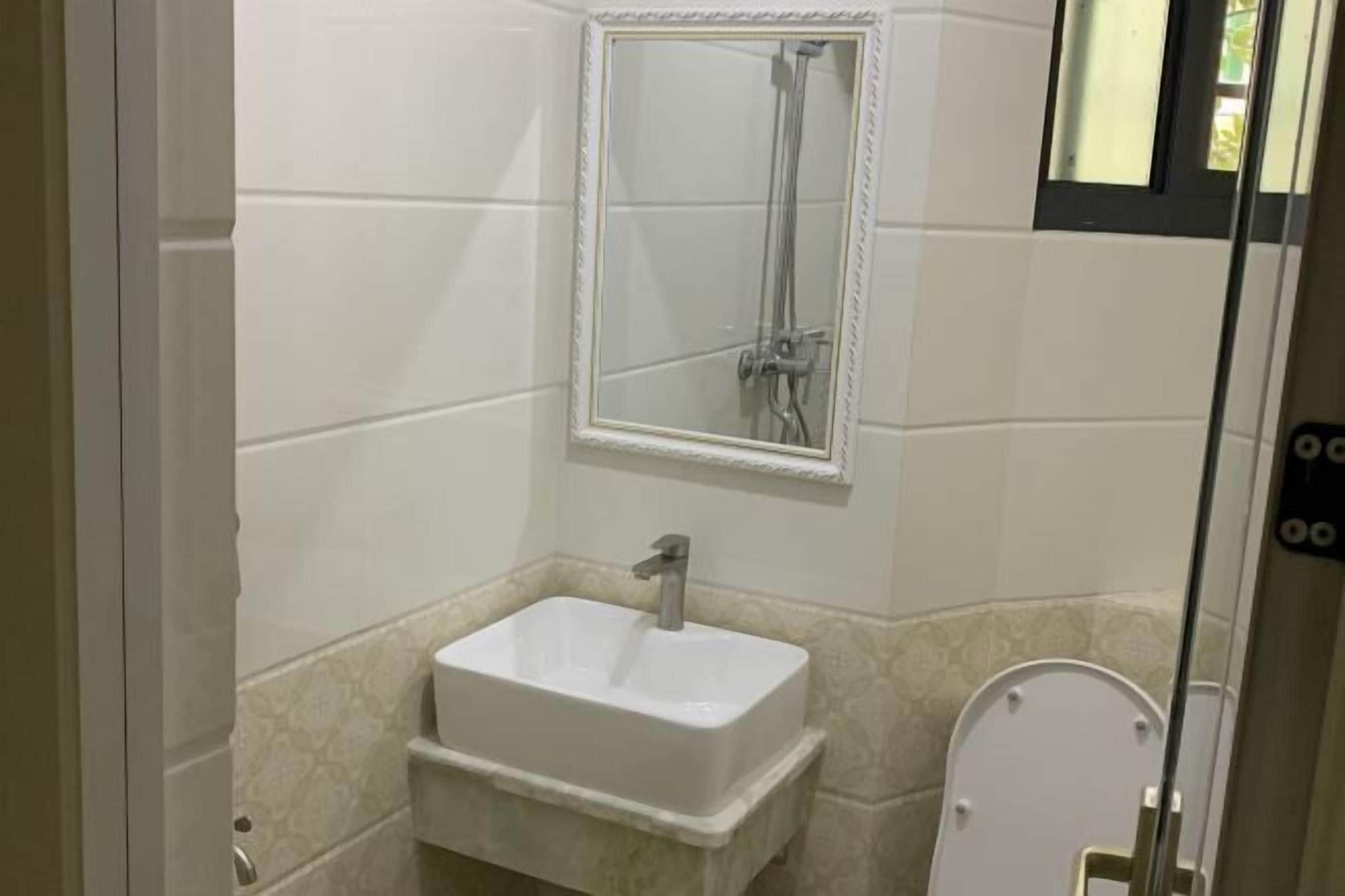 Une salle de bain avec un lavabo blanc, un miroir et une douche.
