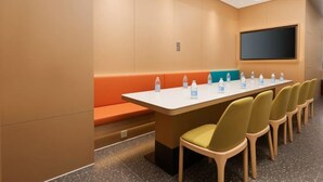 A conference room with a long table, chairs, a screen, and a seating area. - Qingmu Hotel (Nanjing Wutaishan Guangzhou Road Suiyuan Building) (Nanjing)