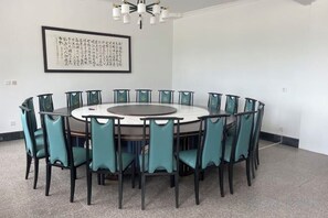 Una sala conferenze con un tavolo rotondo e sedie, un'opera d'arte incorniciata al muro e un lampadario.