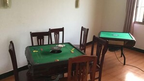 Une pièce équipée d’une table de billard, de chaises et d’une petite table recouverte d’un drap de feutre vert.
