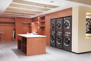 A laundry room with a wooden counter and four wall-mounted washing machines. - Landmark International Hotel(East Railway Station Tianhe Sport Center Branch) (Guangzhou)