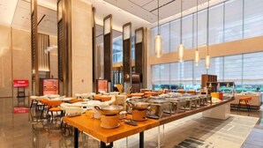 Un hall d’hôtel moderne avec un long buffet, un espace salon et de grandes fenêtres.