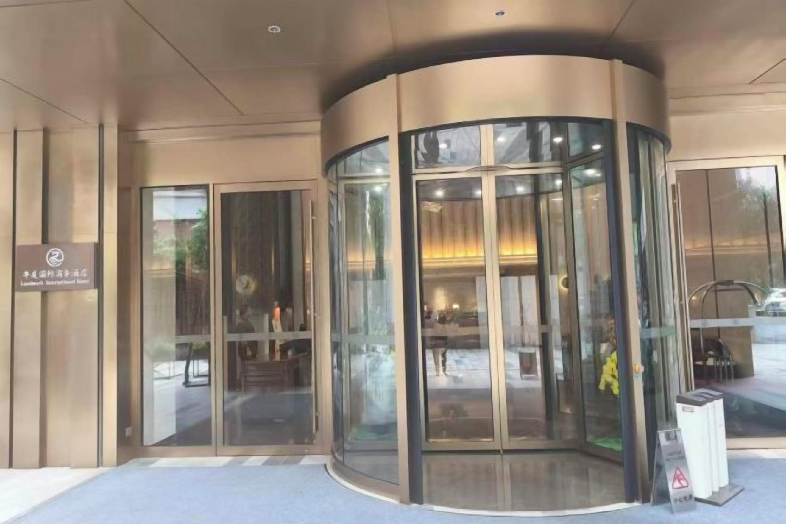A revolving door entrance with glass panels and a sign above it.