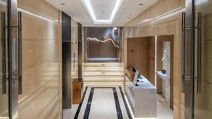 Un hall d’hôtel moderne avec un sol en marbre, un comptoir d’accueil et un escalier menant aux étages supérieurs.