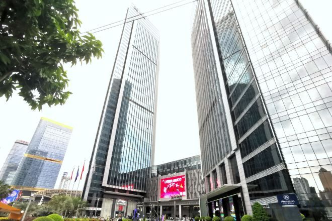 A modern building with a glass facade and a prominent digital billboard.