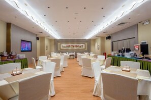 A conference room with rows of tables and chairs, a large screen, and a stage with a banner. - Landmark International Hotel(East Railway Station Tianhe Sport Center Branch) (Guangzhou)