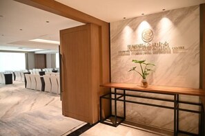 Un salón de conferencias con pared de mármol y un mostrador de recepción de madera.