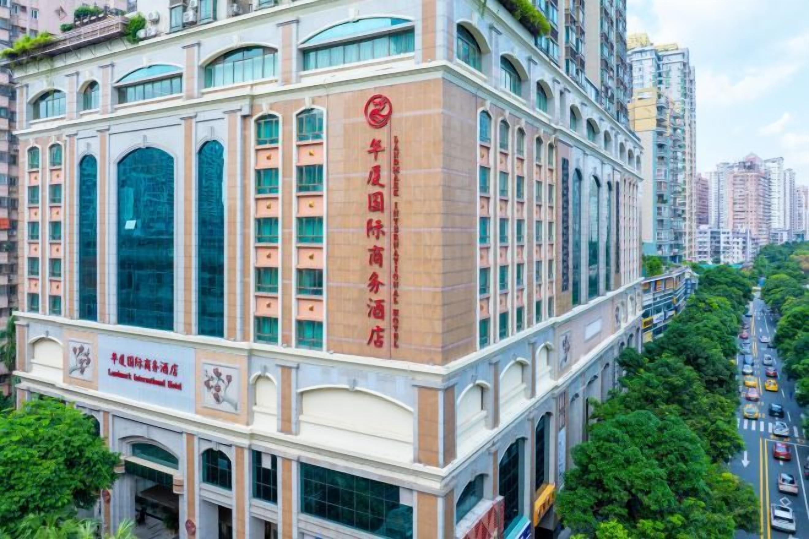 A multi-story hotel with a prominent red sign on the facade, large windows, and a view of the surrounding urban area.