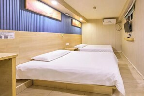 A hotel room with two beds, a wooden headboard, a flat-screen TV, and a wall-mounted air conditioner.