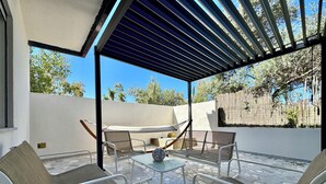 An outdoor patio with a pergola, seating area, and a hammock. - Le Corti Sarde Beach Deluxe (Bari Sardo)