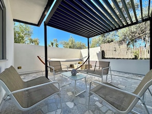 An outdoor patio with a pergola, seating area, and a hammock.