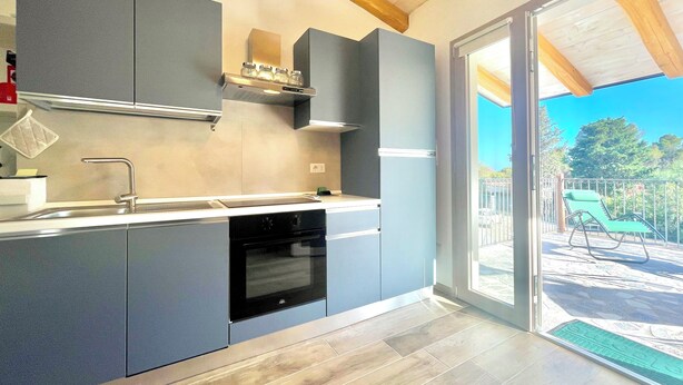 A modern kitchen with grey cabinets, a stainless steel sink, and a built-in oven. - "Le Corti Sarde Beach Apartments" (Bari Sardo)