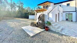 A modern house with a stone staircase, a large rock feature, and a potted plant. - "Le Corti Sarde Beach Apartments" (Bari Sardo)