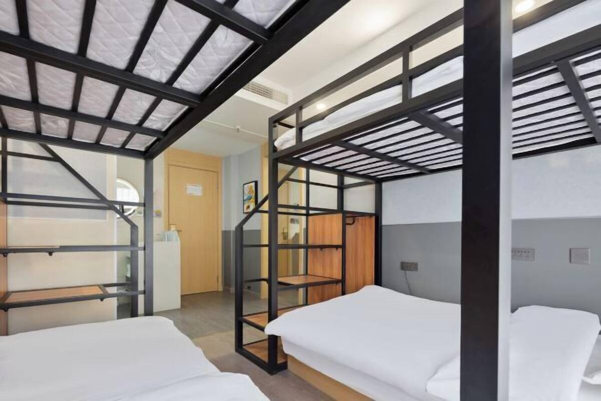 Ein Zimmer mit Etagenbetten, einem Holztisch und einer Tür zu einem weiteren Raum.
