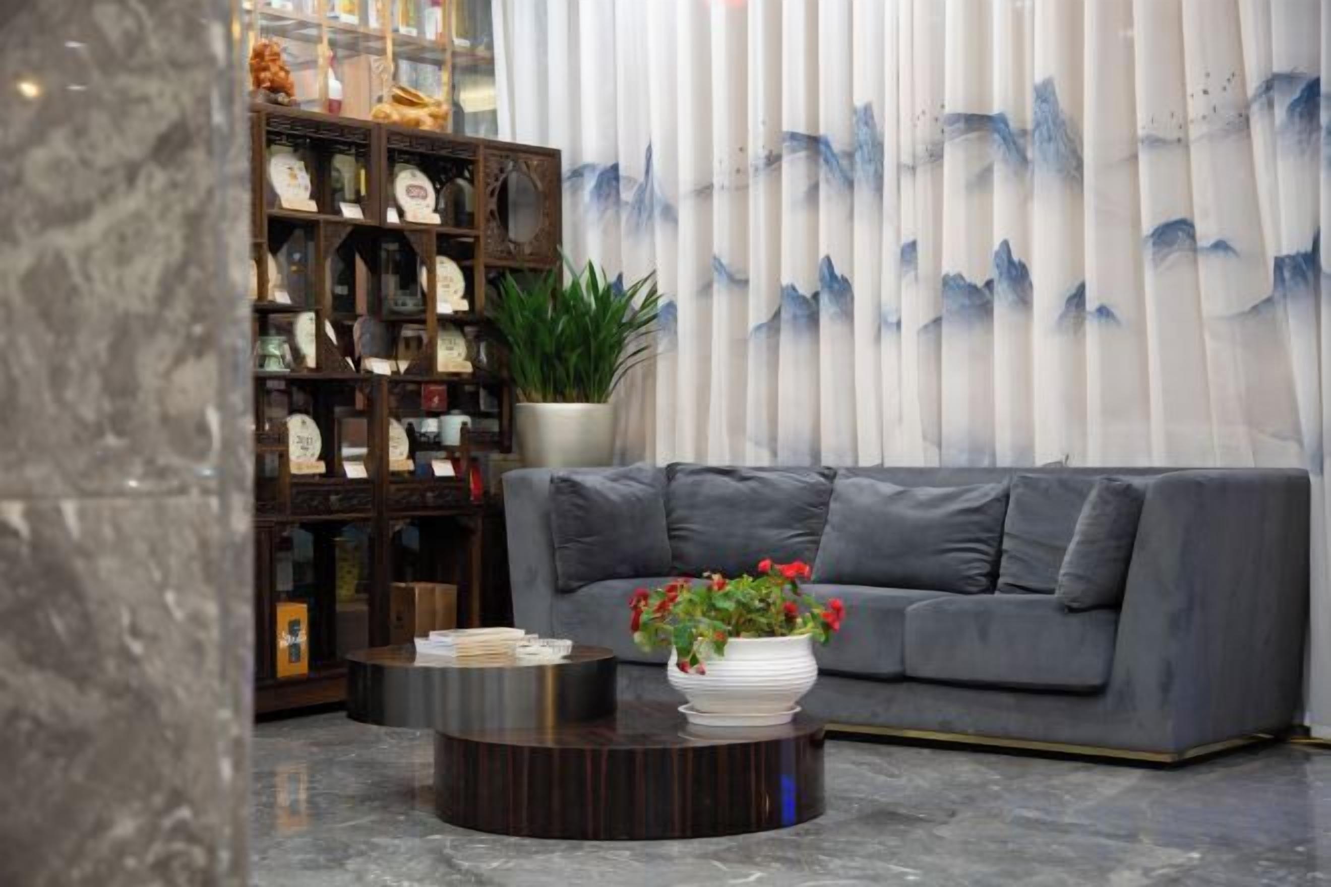 Una sala de estar con un sofá gris, una mesa de centro con un florero y una estantería con diversos objetos.