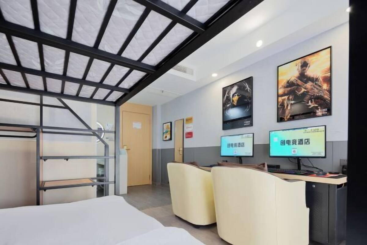 Ein Hotelzimmer mit Stockbetten, einem Schreibtisch mit Computern und Postern an der Wand.