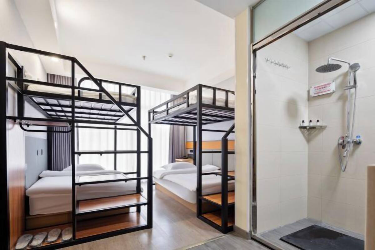 Ein Hotelzimmer mit Stockbetten, einer Dusche und einer kleinen Sitzecke.