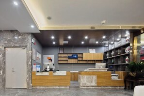Un espace d’accueil doté d’un sol en marbre, d’un comptoir en bois et d’étagères ornées d’objets décoratifs.