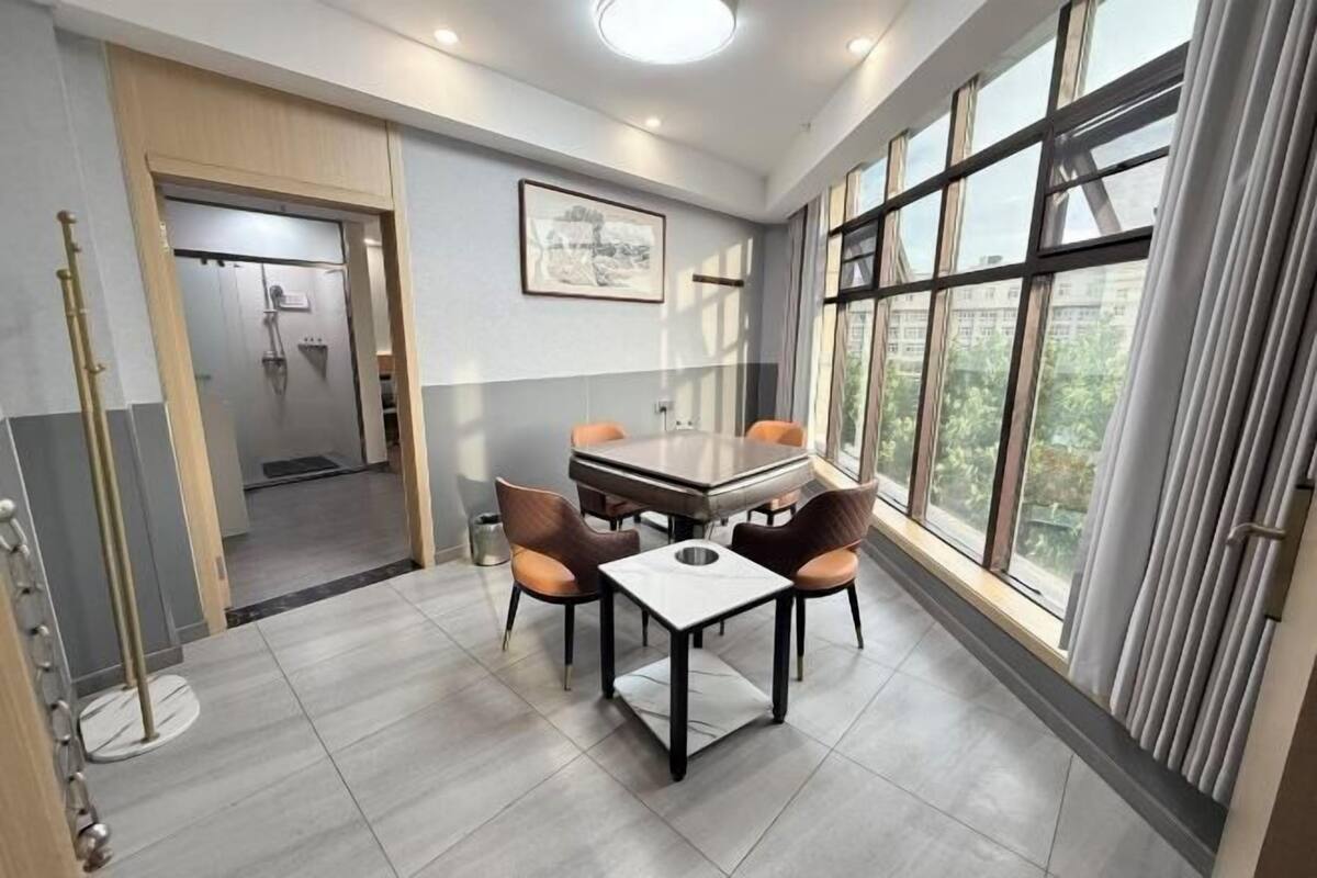 Ein moderner Essbereich mit Tisch und Stühlen, ein Duschbad und große Fenster mit Vorhängen.