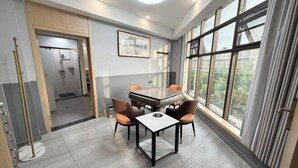 Un espace repas moderne avec une table et des chaises, une salle de douche et de grandes fenêtres équipées de rideaux.