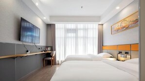 Une chambre d’hôtel équipée d’un lit, d’un bureau, d’une chaise, d’une télévision et d’une fenêtre avec des rideaux.