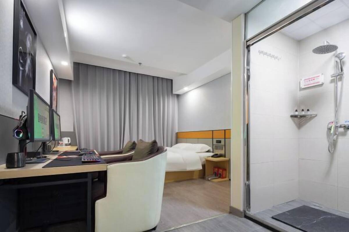 Ein Hotelzimmer mit Schreibtisch, Stuhl, Bett und einer Dusche.