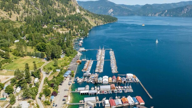Vue aérienne d’une marina où sont amarrés des bateaux, le tout étant entouré de collines et surplombé par un ciel dégagé.