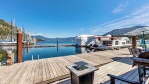 Une jetée en bois offrant une vue sur un port de plaisance, un bateau blanc amarré et un ciel bleu dégagé.