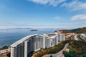A high-rise residential building complex with multiple balconies, situated near a body of water and surrounded by greenery. - Huidong Sumao Homestay (Xunliao Bay) (Huidong)