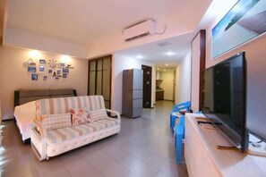 A living room with a sofa, a television, and a kitchen area in the background. - Huidong Sumao Homestay (Xunliao Bay) (Huidong)