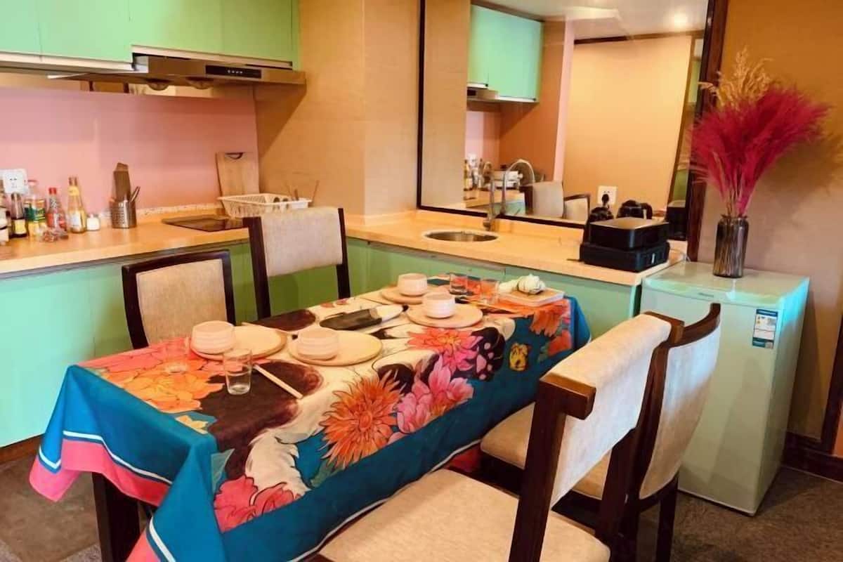 A dining area with a table set for two, a refrigerator, and a microwave.