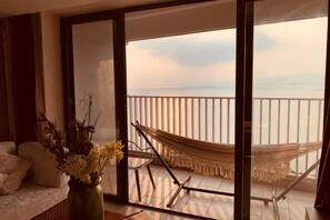 Uma varanda com rede, sofá e um vaso de flores.