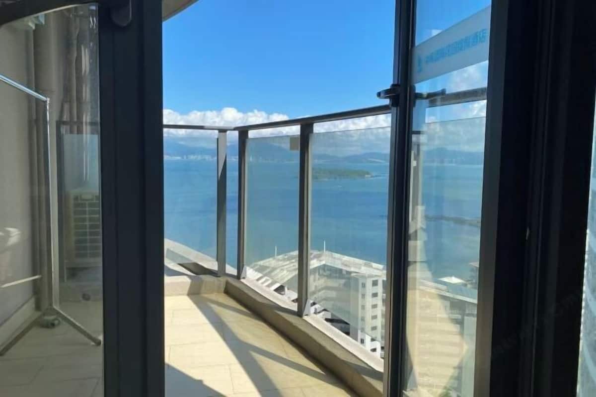 A high-rise building with large windows offering a view of a coastal area.