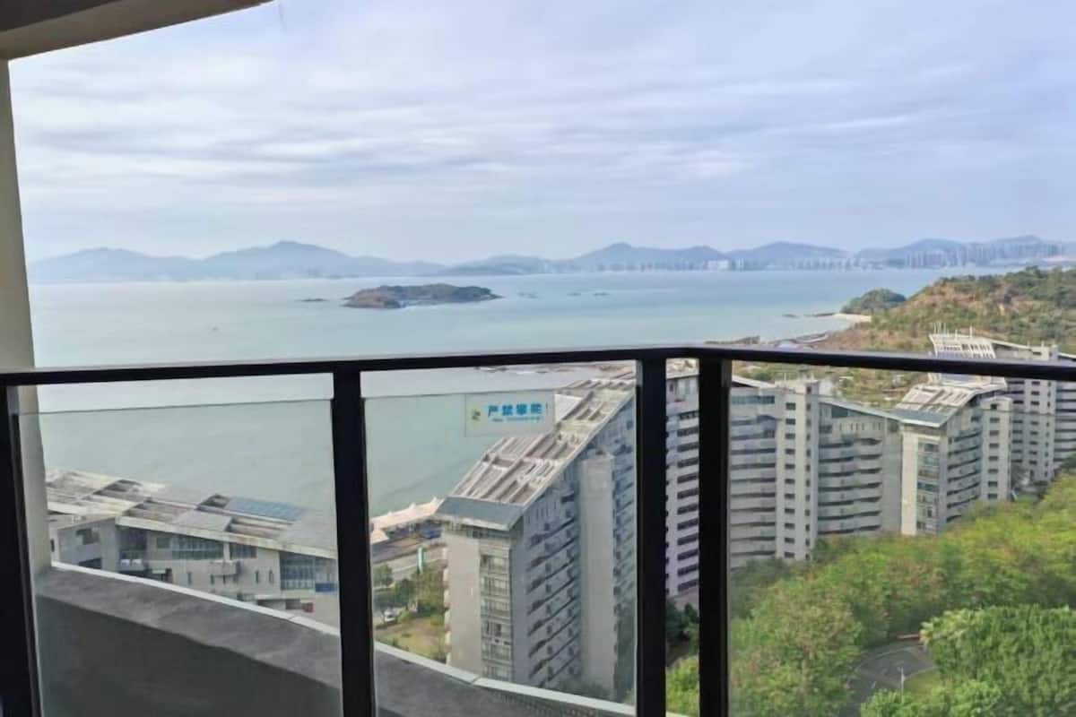 A high-rise building with a view of the sea and distant mountains.