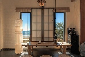 A traditional Japanese room with tatami flooring, a low table, a shoji screen, and a large window.